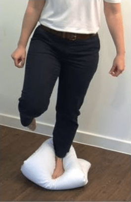 Person balancing on one leg while standing on a cushion