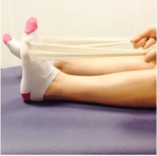 Person doing ankle stretching exercises by pointing and flexing their toes using a towel or bandage. (step 1)