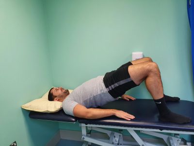 Person lying on their back with their knees bent hip width apart moving into a bridge position