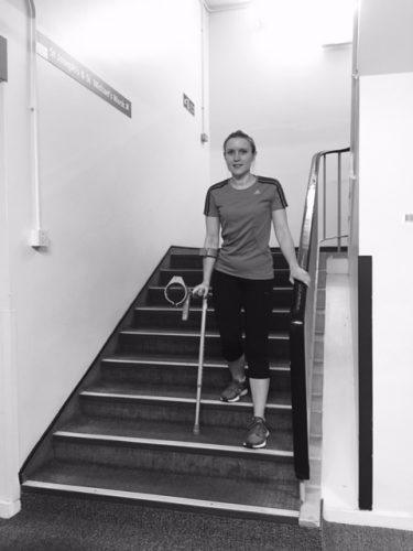 Person walking down stairs using crutches