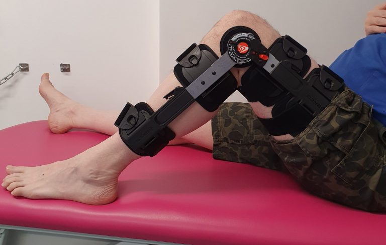 Person with their injured knee bent doing exercises while wearing a T-scope brace