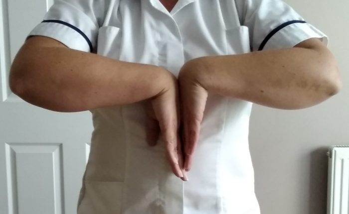 Person standing with their hands in a reverse prayer position
